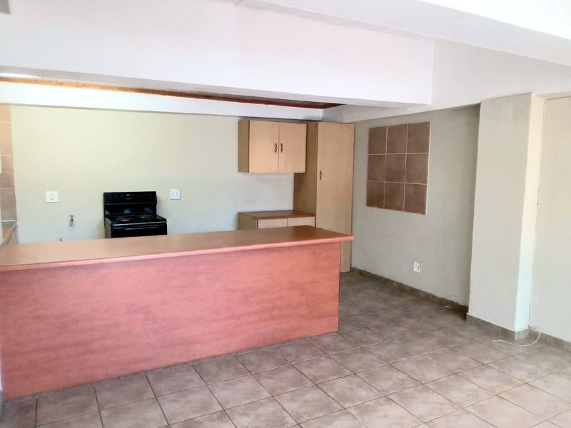 An empty kitchen area featuring tiled flooring, built-in cabinetry, a breakfast bar, and a freestanding stove.