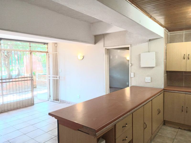 Open plan kitchen and living area featuring built-in cabinetry, tiled floors, and direct access to an outdoor patio through a security gate.