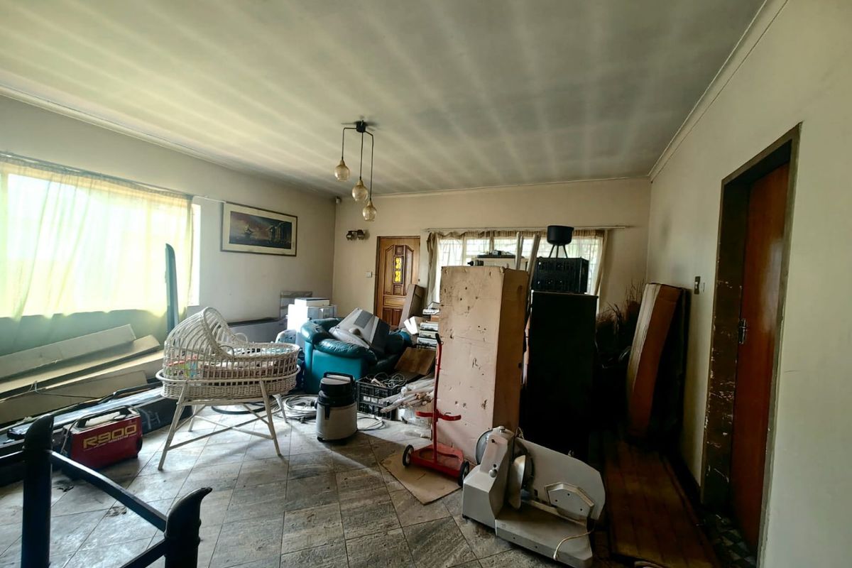 A living room space featuring tiled flooring and a central light fixture, currently used for storage.