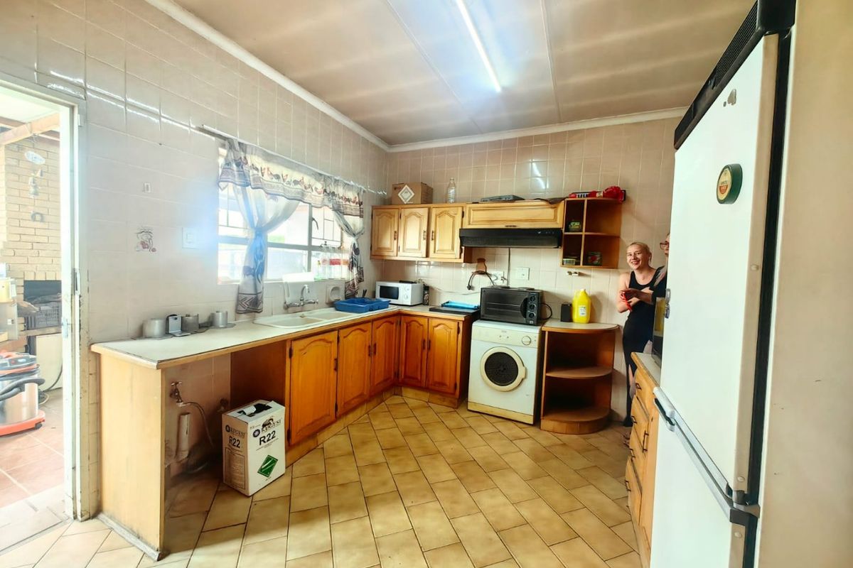 A dated kitchen featuring wooden cabinetry, tiled walls, and tiled flooring, with direct access to an outdoor patio area.