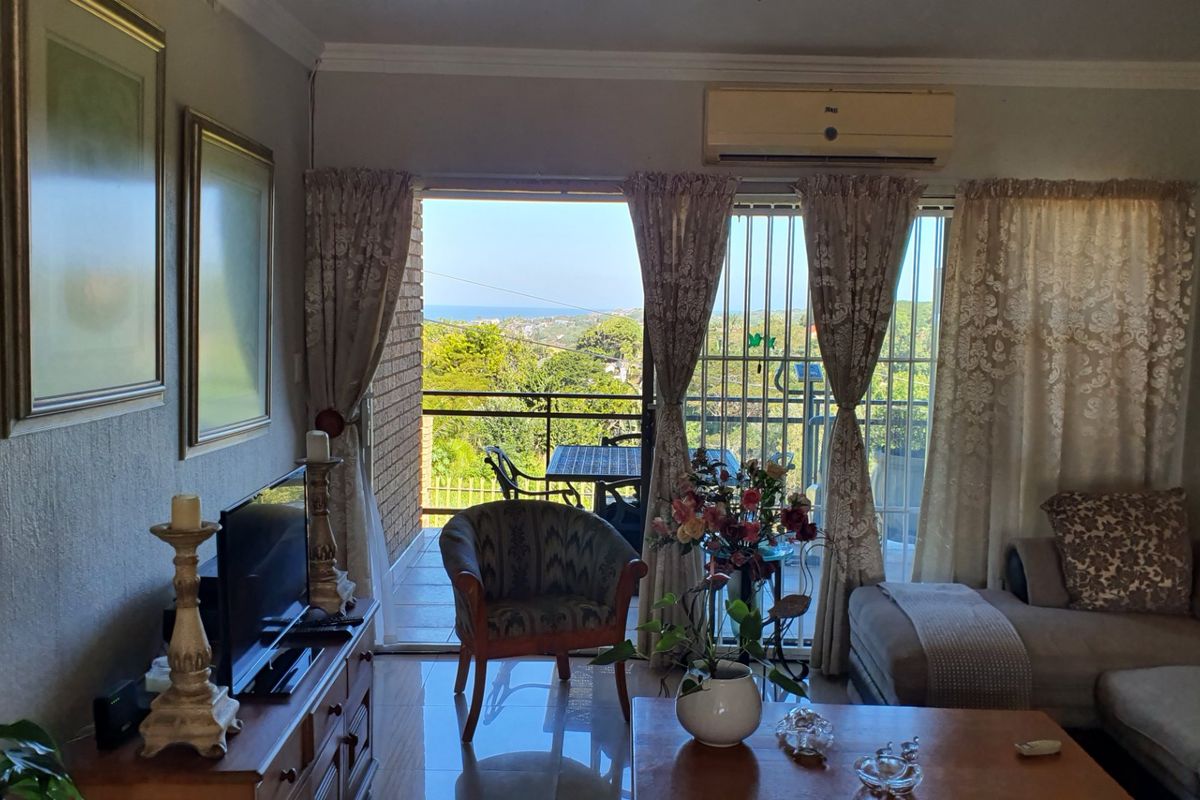 Comfortable living room featuring tiled floors, crown molding, and a split-system air conditioner, with direct access to a balcony offering scenic views.