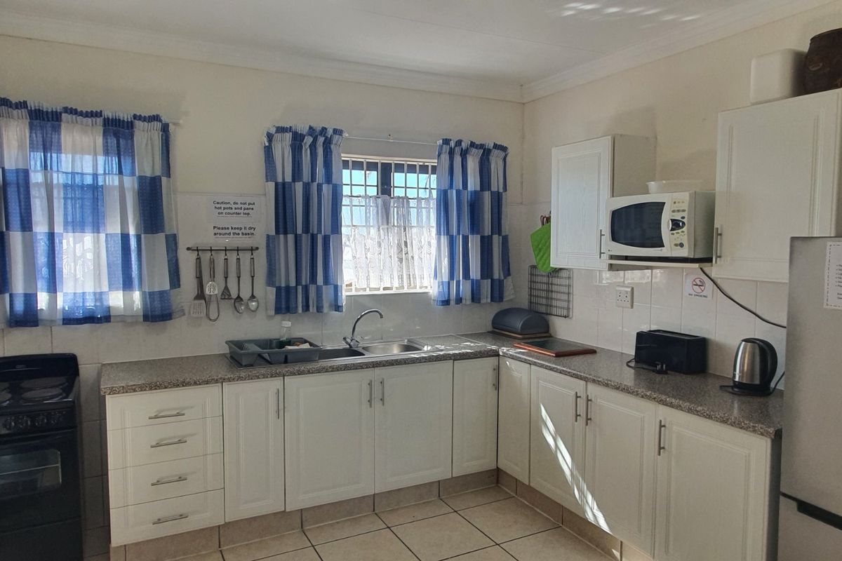 A functional kitchen featuring white cabinetry, laminate countertops, tiled backsplash, and tiled flooring, providing a clean and practical workspace.