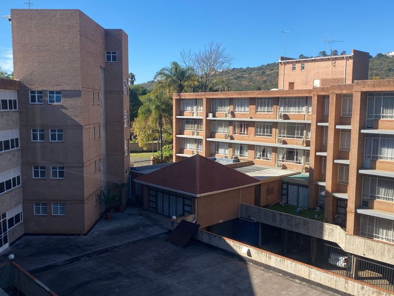 An elevated view of the apartment complex exterior, featuring brick facades, a central courtyard, and surrounding residential building structures.