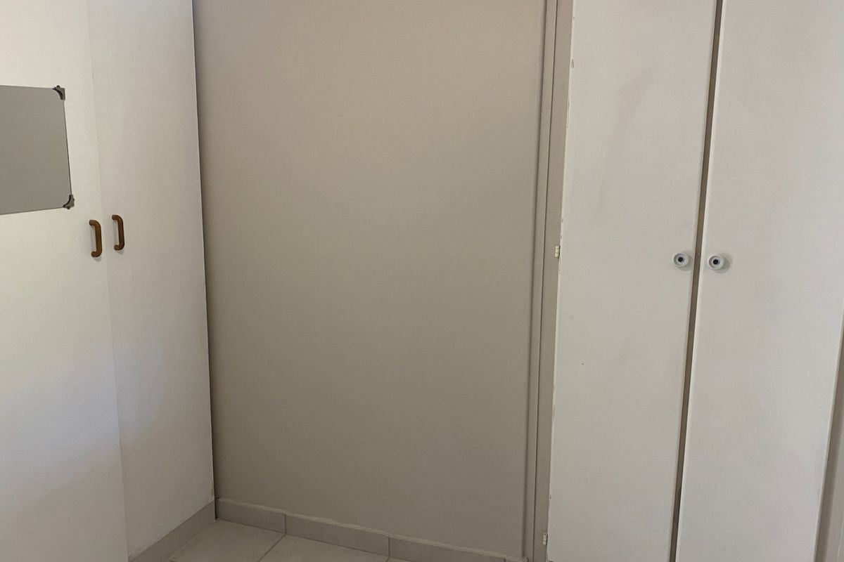 A bedroom interior featuring built-in cupboards and tiled flooring, presenting a clean and neutral space ready for personalization.