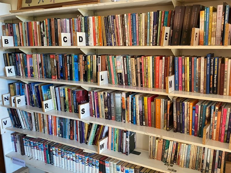 A wall-mounted built-in shelving unit filled with books, featuring alphabetical dividers for organization.