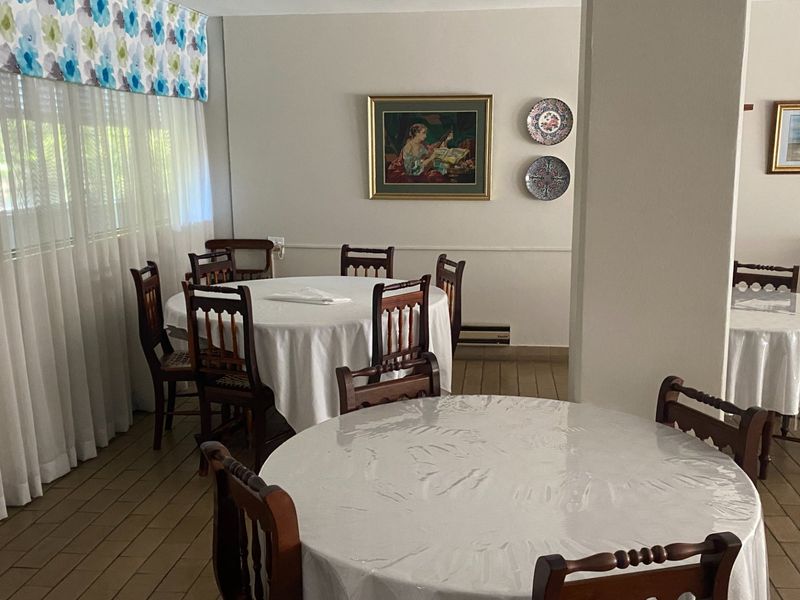 A spacious dining area featuring tiled flooring and neutral walls, suitable for multiple dining tables and seating arrangements.