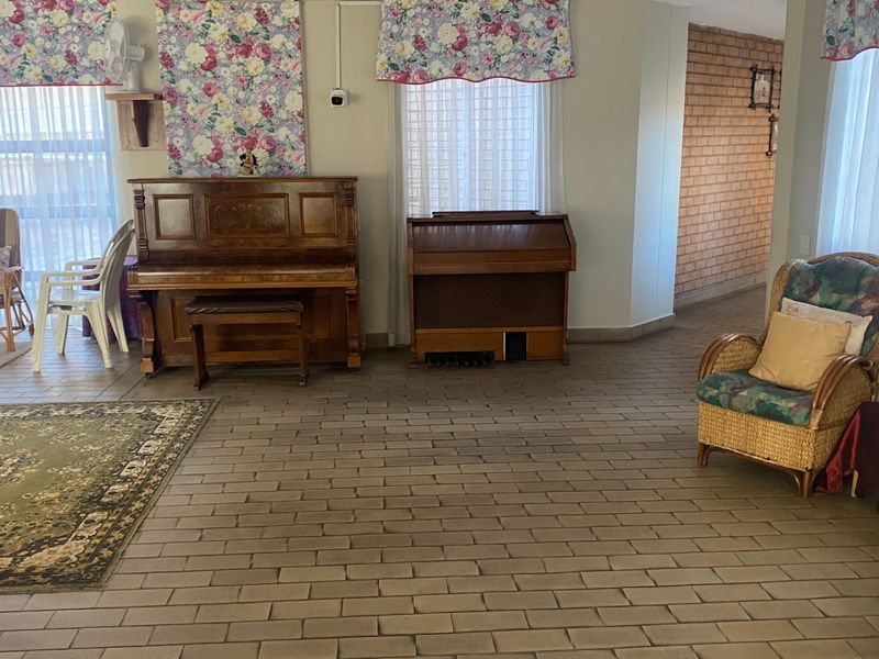 Spacious living area featuring durable brick flooring and an exposed brick feature wall, offering a rustic aesthetic with ample natural light.