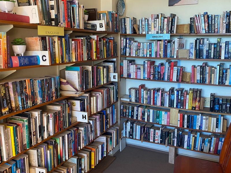 A room featuring extensive built-in shelving units filled with books, organized alphabetically.