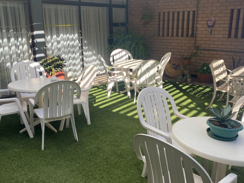 A covered outdoor patio area featuring artificial turf, brick wall detailing, and direct access to the interior through sliding glass doors.