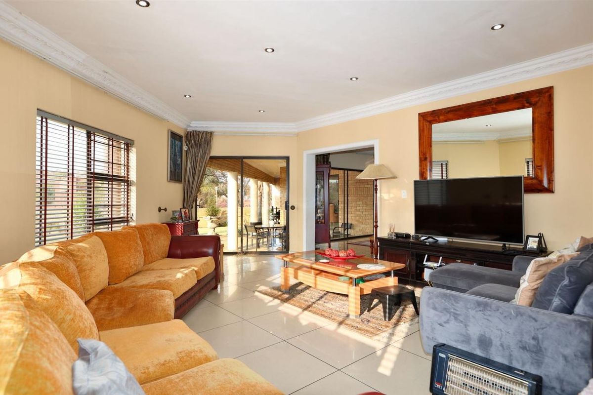 Spacious living room featuring tiled flooring, recessed downlights, decorative ceiling cornice, and sliding glass doors providing access to the outdoor patio area.