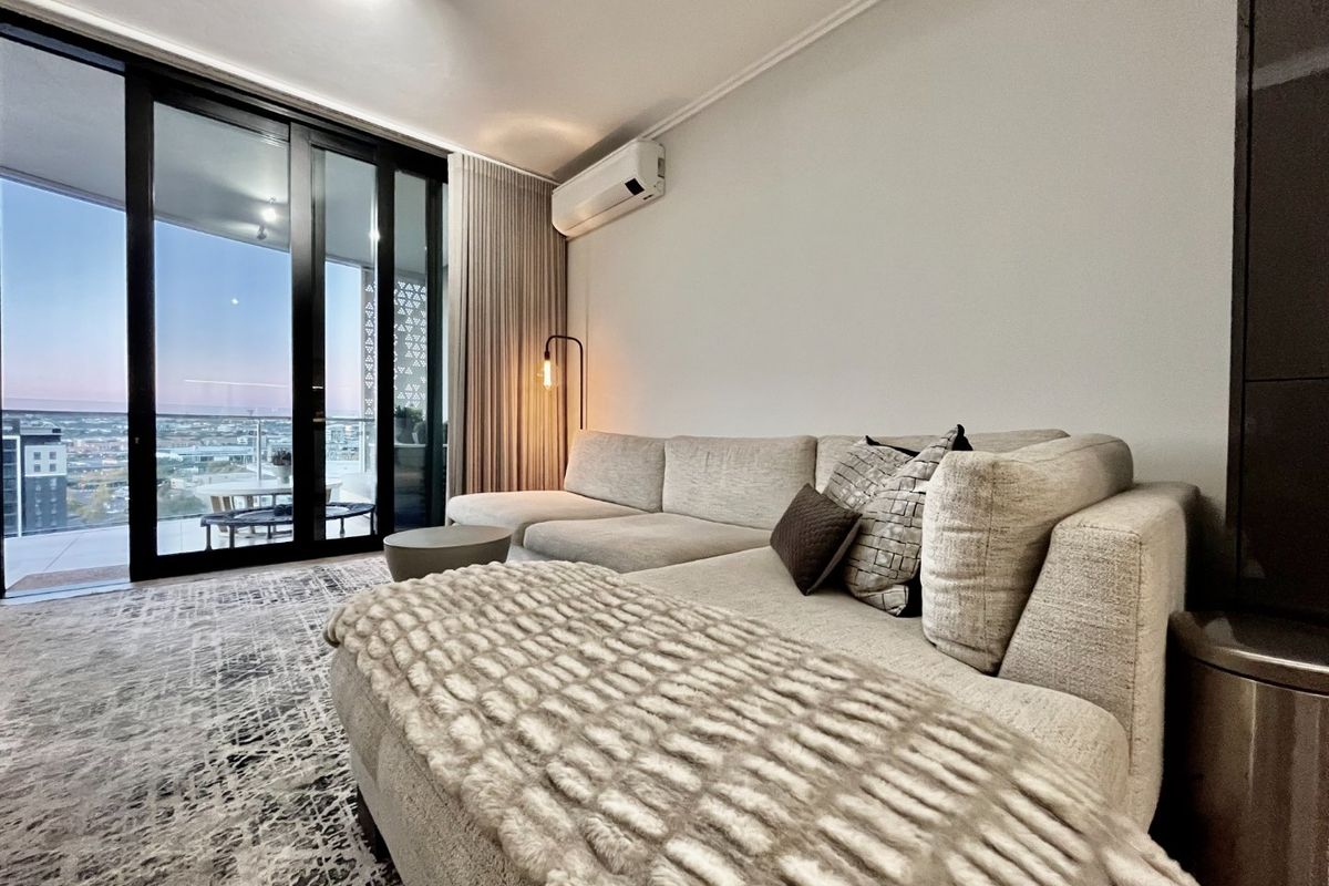 Modern living room featuring a split-system air conditioner and large sliding glass doors that open onto a balcony with expansive views.