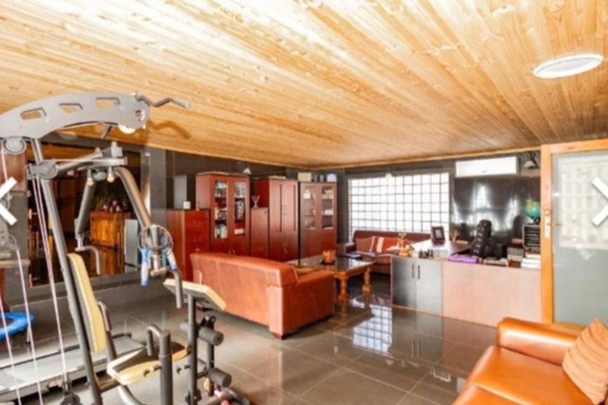 Spacious living area featuring a timber-clad ceiling, tiled flooring, and a glass block window, currently utilized as a multi-purpose room.