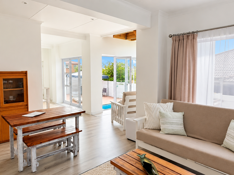 Bright open-plan living area featuring laminate flooring, recessed lighting, and large sliding glass doors providing seamless access to the outdoor patio and pool area.