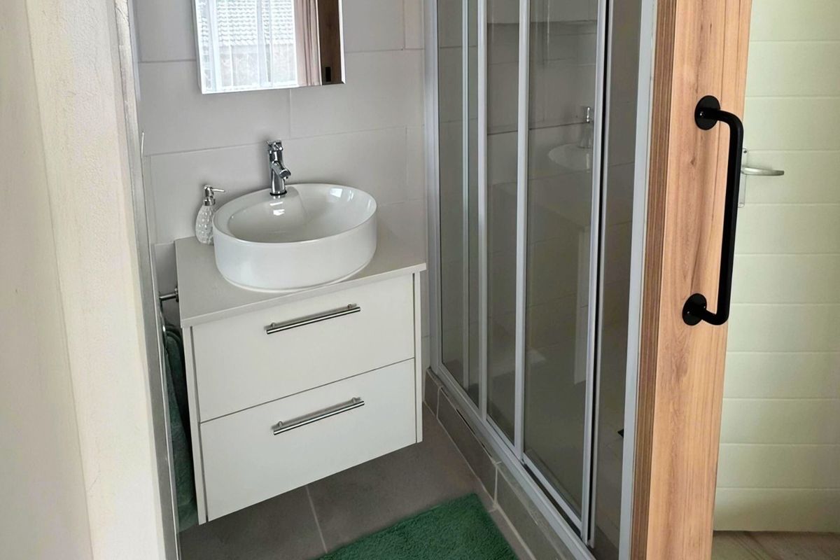 Modern bathroom featuring a white vanity with a vessel sink, a glass-enclosed shower, and a sliding wooden barn door.