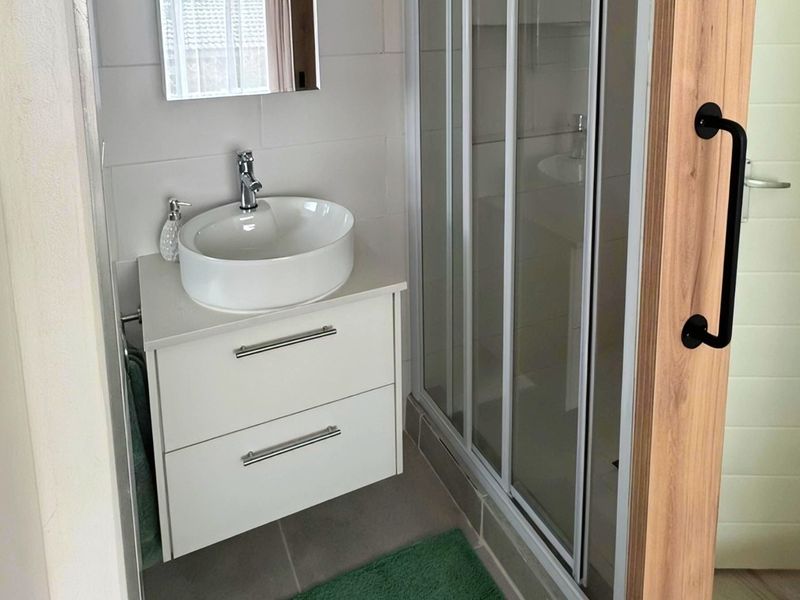 Modern bathroom featuring a white vanity with a vessel sink, a glass-enclosed shower, and a sliding wooden barn door.