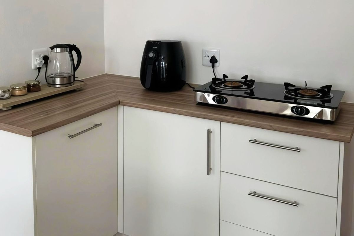A clean, modern kitchen corner featuring white cabinetry, wood-look laminate countertops, and a built-in gas hob.