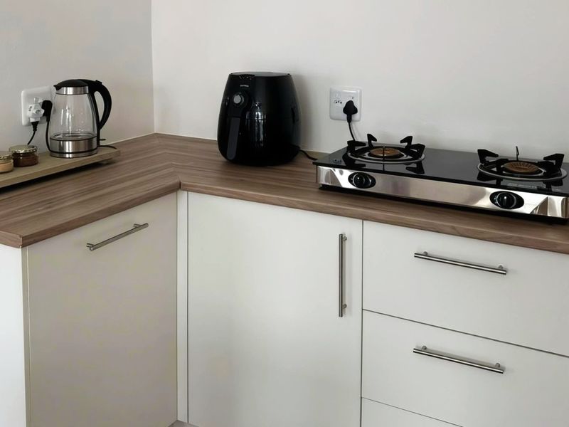 A clean, modern kitchen corner featuring white cabinetry, wood-look laminate countertops, and a built-in gas hob.