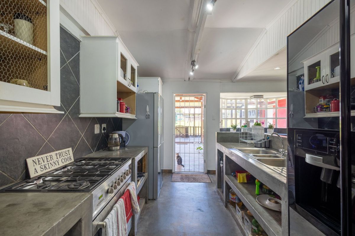 Rustic kitchen featuring concrete countertops, gas hob, built-in oven, and double sink, with direct access to the rear outdoor area.