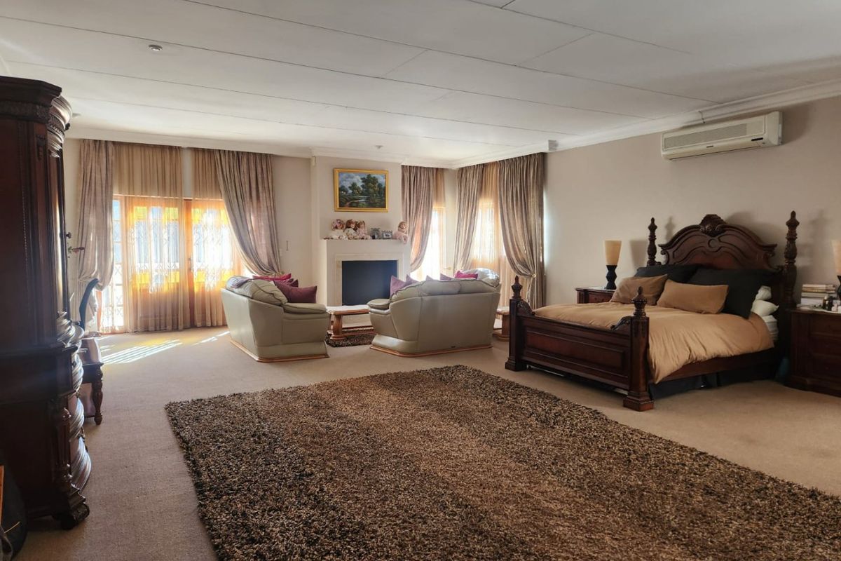 Spacious master bedroom featuring a built-in fireplace, wall-mounted air conditioning unit, and large windows with natural light.