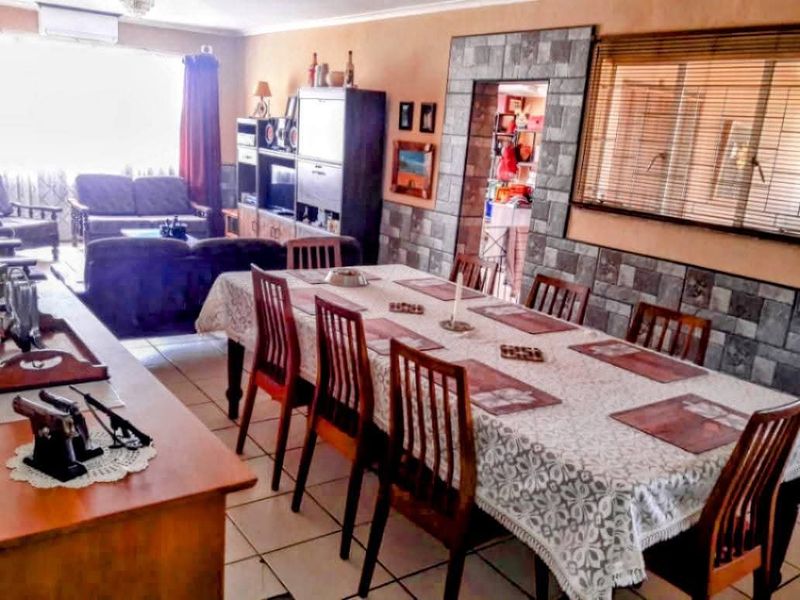 Open-plan dining and living area featuring tiled flooring, a stone-clad feature wall, and split-system air conditioning.