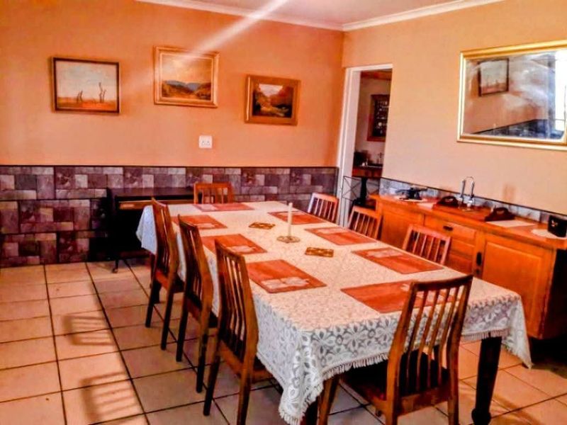 A dining room featuring tiled flooring, stone-look wall cladding, and a built-in wooden sideboard, offering a traditional aesthetic.