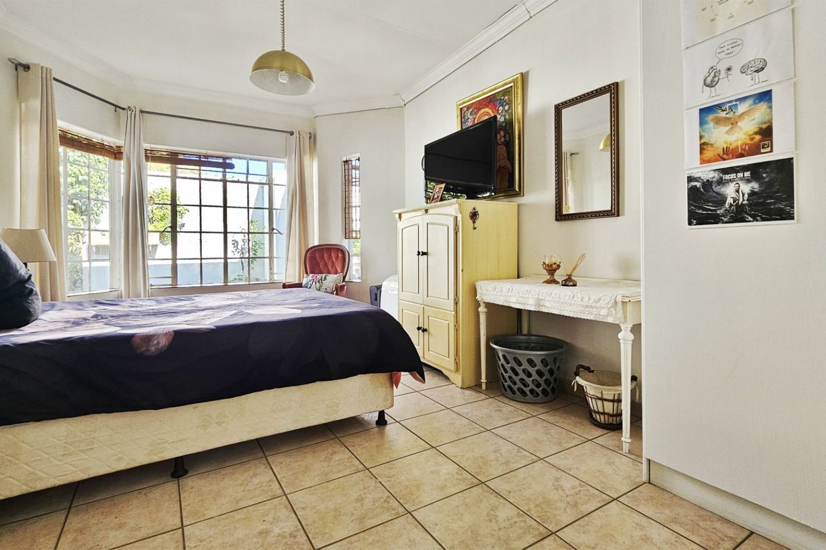 Spacious bedroom featuring tiled flooring, built-in cupboards, and a large bay window that allows for ample natural light.
