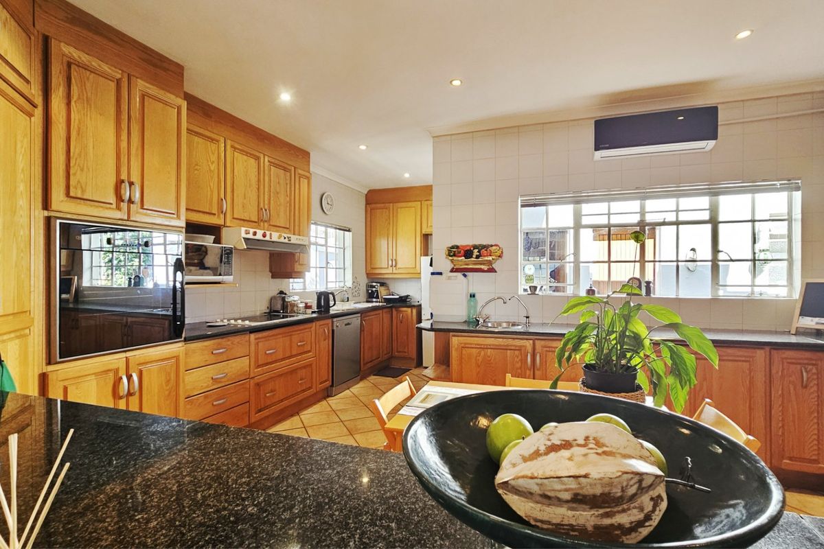 Spacious kitchen featuring extensive wooden cabinetry, granite countertops, built-in oven, and integrated appliances, offering a functional layout with ample storage and workspace.