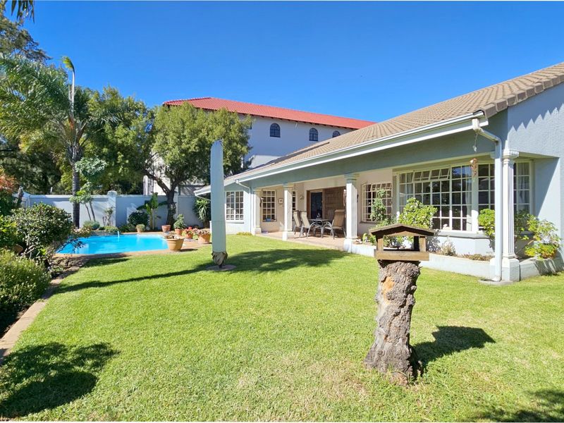 Rear view of the townhouse featuring a covered patio, well-maintained lawn, and a private swimming pool.
