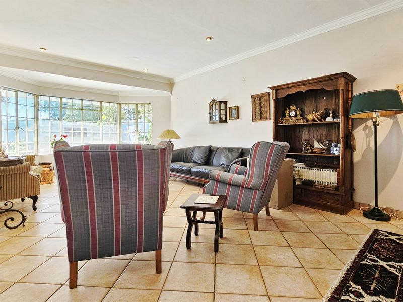 Spacious living room featuring large bay windows, ceramic tile flooring, and recessed lighting, offering a bright and comfortable area for relaxation.