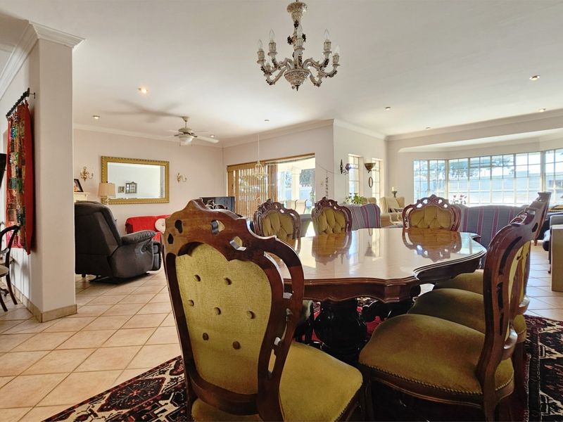 Spacious open-plan living and dining area featuring ceramic tiled flooring, recessed lighting, a decorative chandelier, and large windows providing ample natural light.