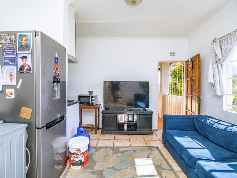 Open plan living area featuring tiled flooring and direct access to an exterior space through a timber door with security gate.