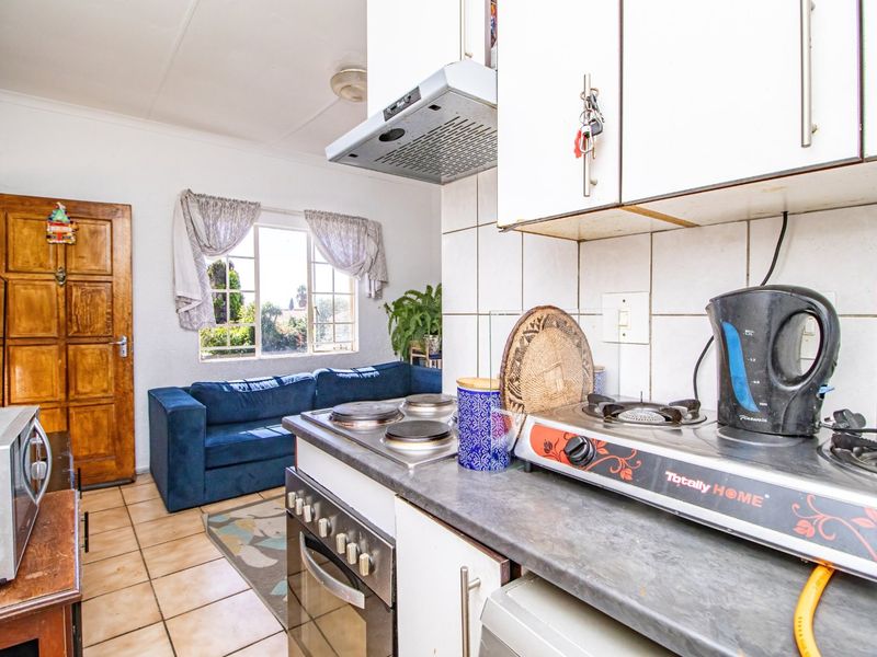 Open-plan kitchen and living area featuring tiled flooring, built-in oven, extractor fan, and direct access to the living space.