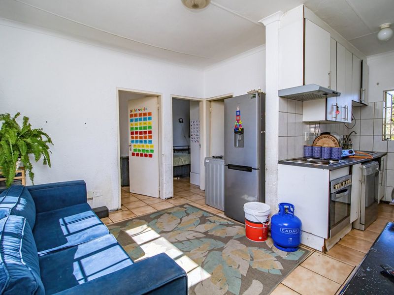 Open-plan living and kitchen area featuring tiled flooring, built-in cabinetry, and integrated cooking appliances, offering a functional layout for daily living.