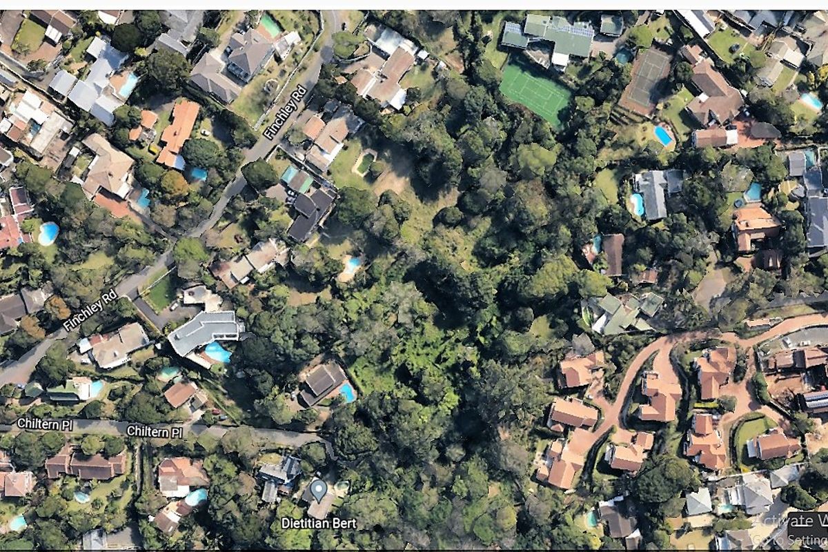 An aerial view of a residential area showing surrounding properties, mature trees, and local street infrastructure.