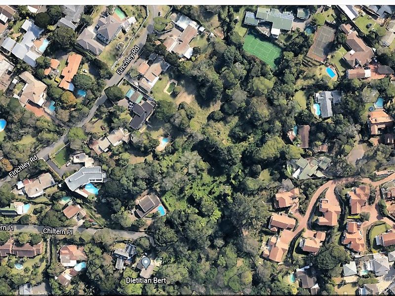 An aerial view of a residential area showing surrounding properties, mature trees, and local street infrastructure.
