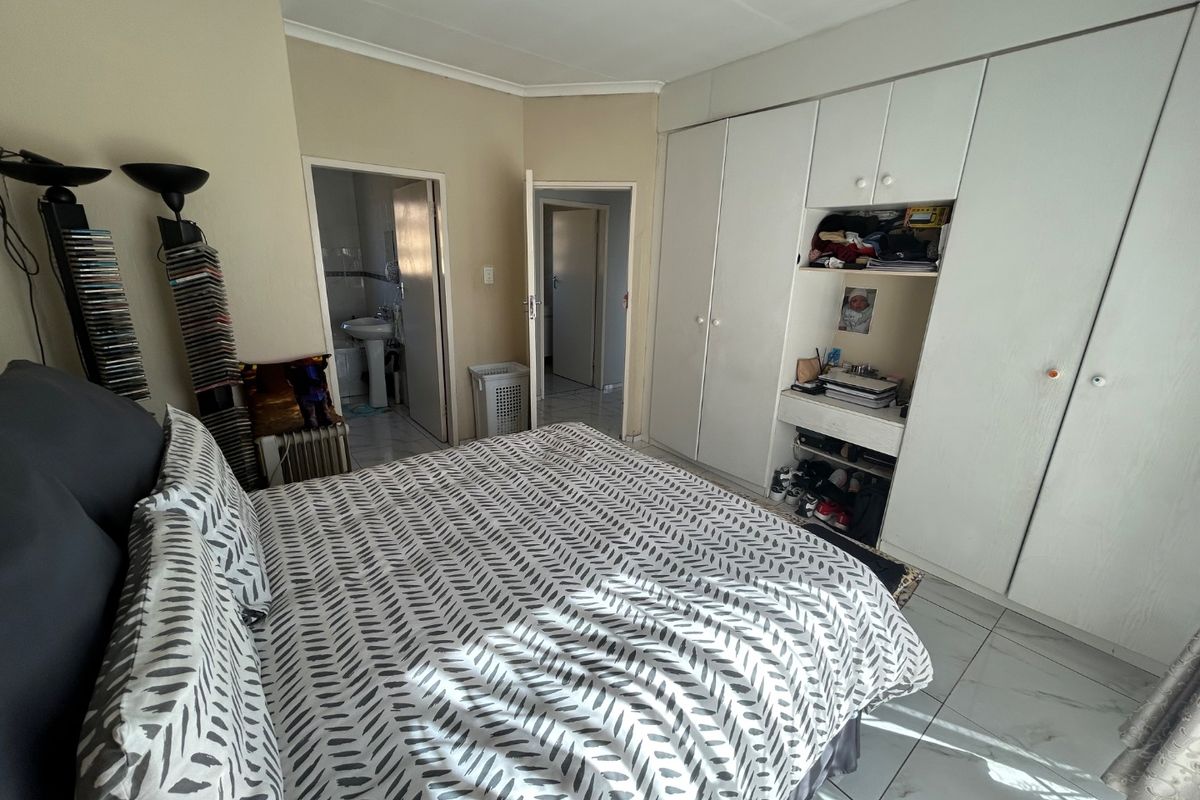 A bedroom featuring built-in cupboards, tiled flooring, and direct access to an en-suite bathroom.