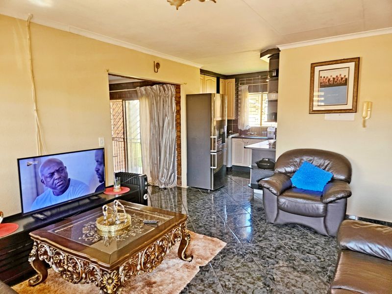 Open-plan living area featuring tiled flooring and a connected kitchen space with built-in cabinetry.