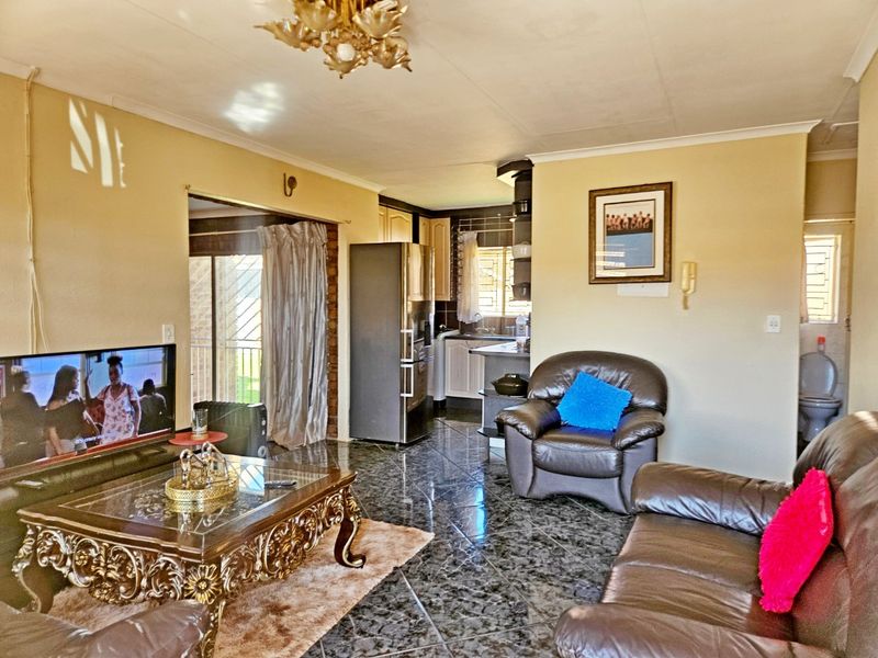 Open plan living area featuring tiled flooring and a connected kitchen space, providing a functional layout for daily living.