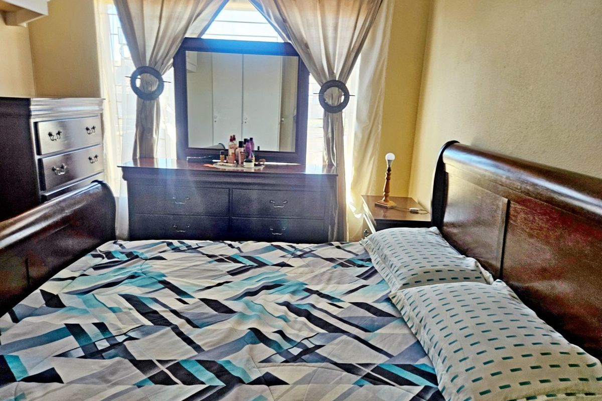 A bedroom featuring built-in cupboards and security bars on the window, providing a functional space with standard finishes.