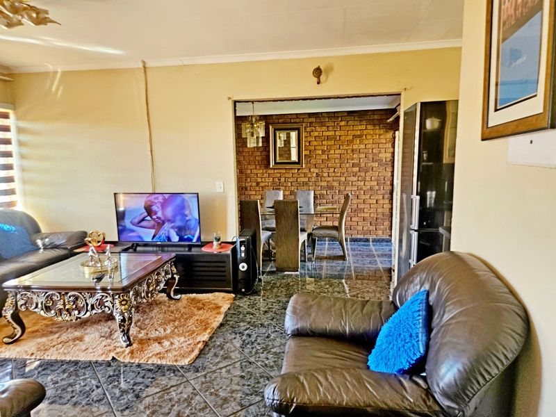 Open plan living and dining area featuring tiled flooring and a distinctive exposed brick feature wall.