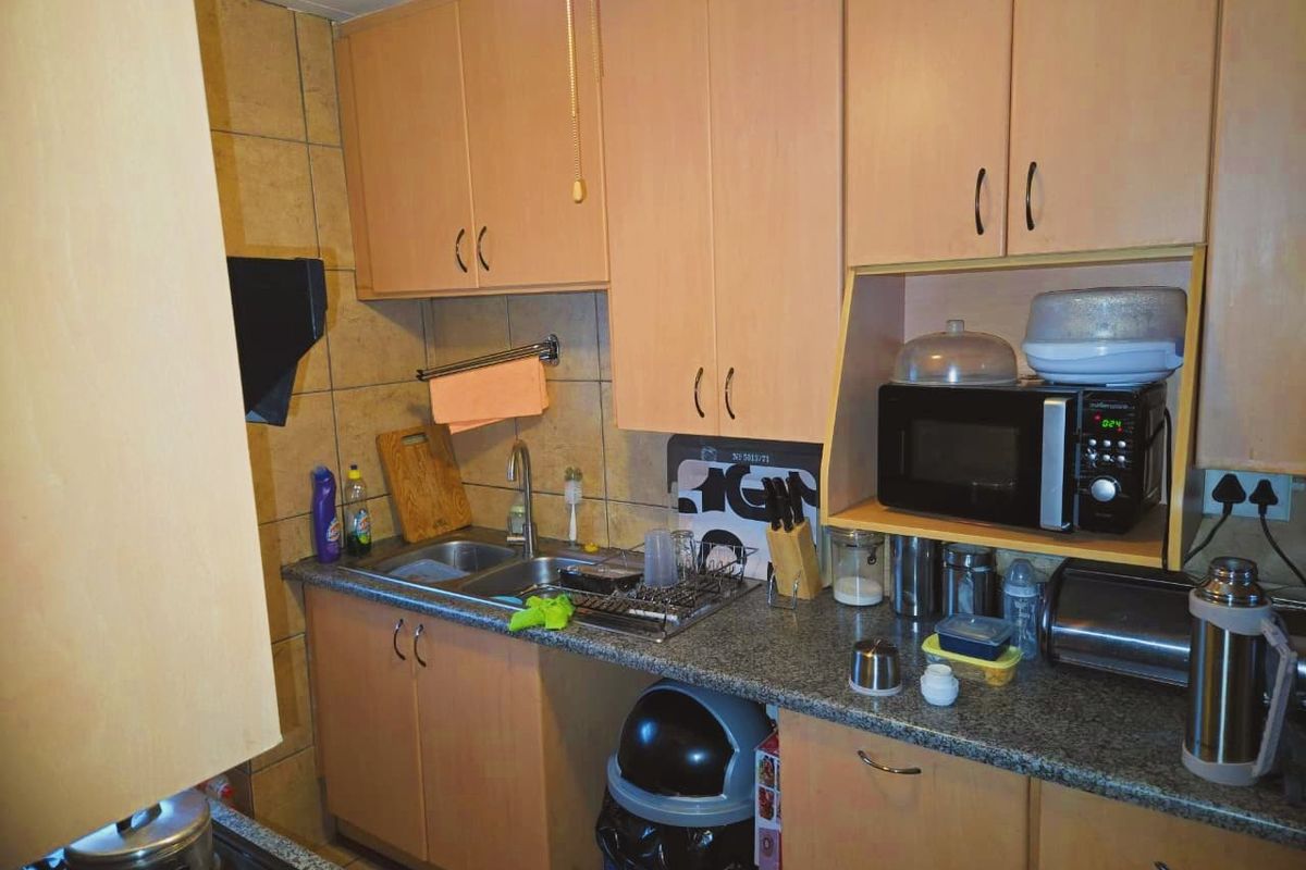 A compact kitchen featuring laminate cabinetry, granite countertops, and a tiled backsplash, providing functional storage and workspace.
