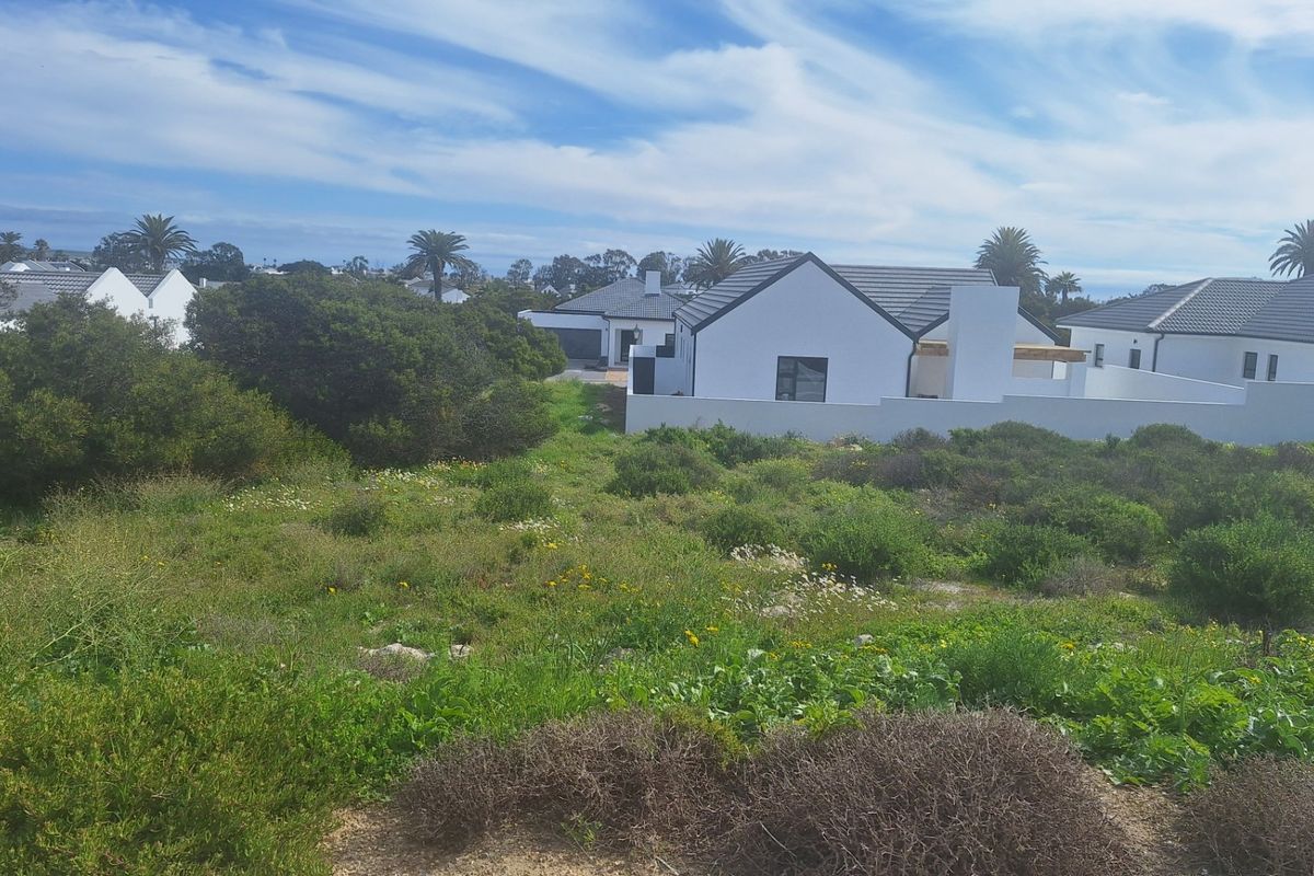 A view of a vacant residential plot featuring natural vegetation and surrounding boundary walls in a developed estate setting.