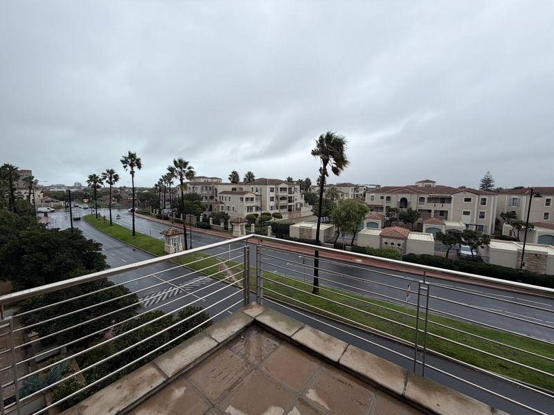 Elevated balcony view overlooking a suburban street and surrounding residential complex under an overcast sky.
