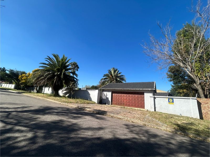 Street view of the property showing a perimeter wall, paved driveway, and a single garage door with a tiled roof.