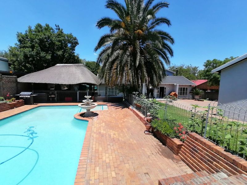 Spacious outdoor pool area featuring a swimming pool, brick paving, a decorative fountain, and a thatched lapa, perfect for outdoor entertaining.