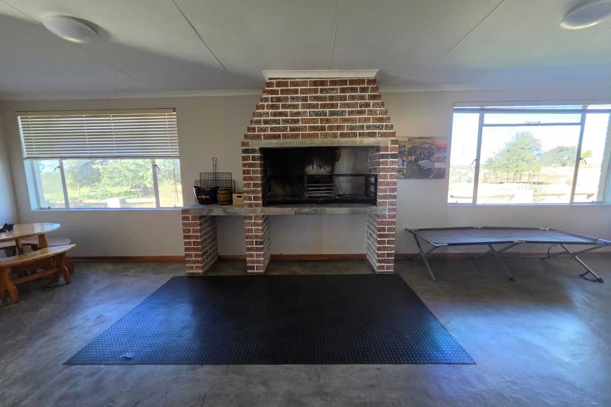 Spacious living area featuring a prominent built-in brick fireplace, polished concrete floors, and large windows providing ample natural light.