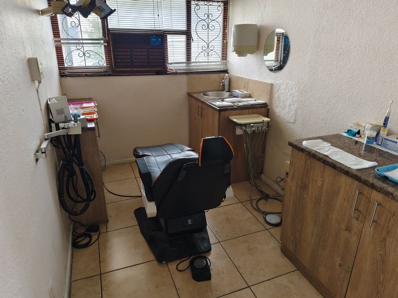 A functional clinical utility space featuring built-in cabinetry, a sink, tiled flooring, and wall-mounted equipment, suitable for medical or professional use.