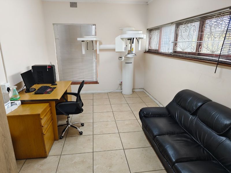 A functional commercial office space equipped with specialized dental imaging infrastructure, featuring tiled flooring and window security treatments.