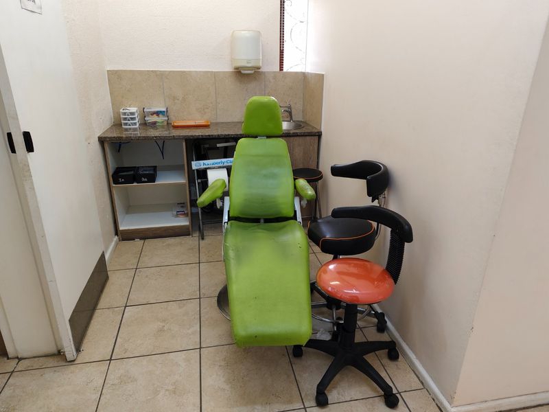 A functional utility or treatment room featuring built-in cabinetry, a granite countertop with an integrated sink, and durable tiled flooring.