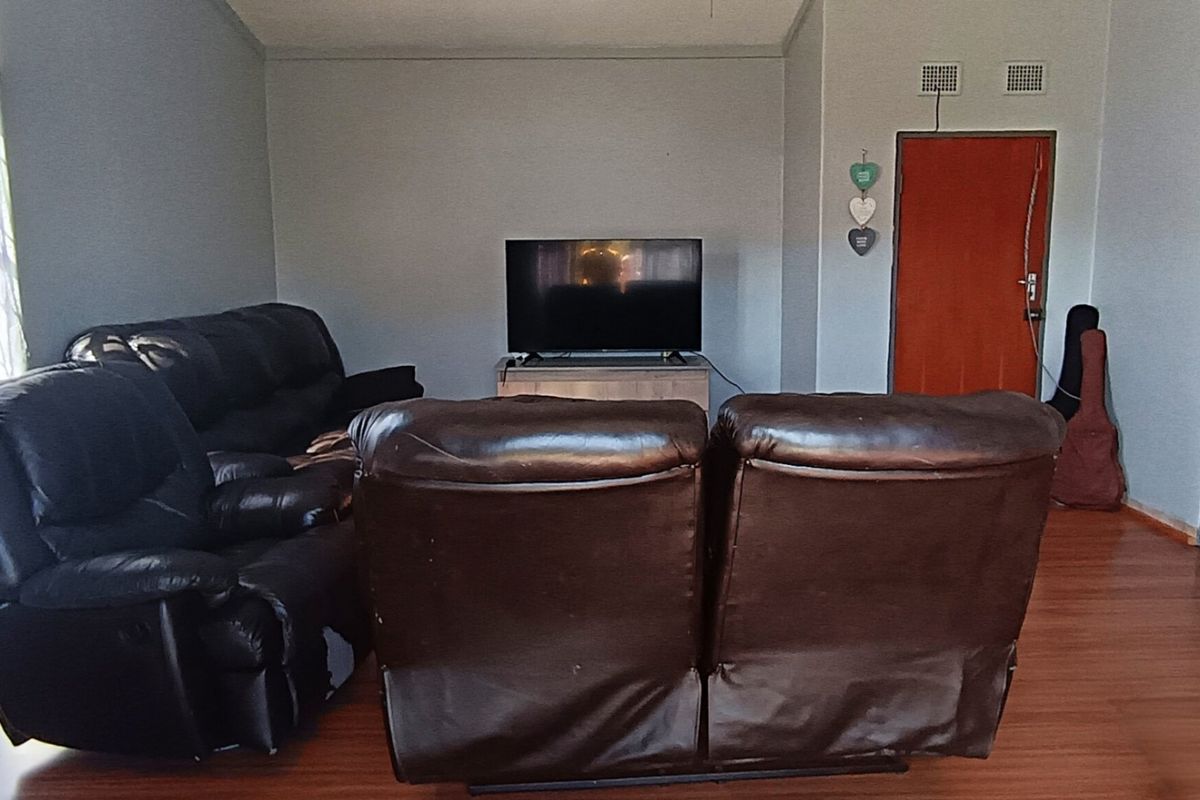 A living room featuring laminate flooring and neutral wall finishes, providing a functional space for relaxation.